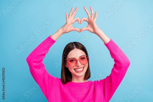 Portrait of attractive cheerful girl showing heart sign health care amour cupid isolated over bright blue color background © deagreez