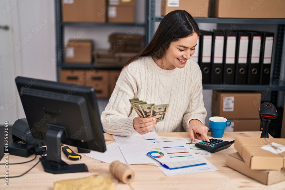 Young woman ecommerce business worker counting dollars at office