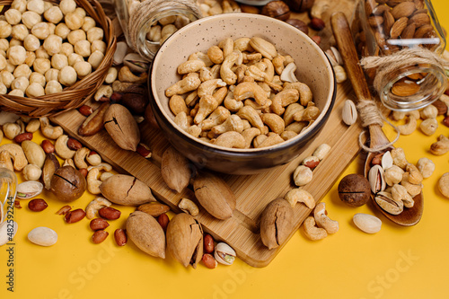 Mix of different types of dried nuts in compositions on a yellow background. Top view. Flat lay