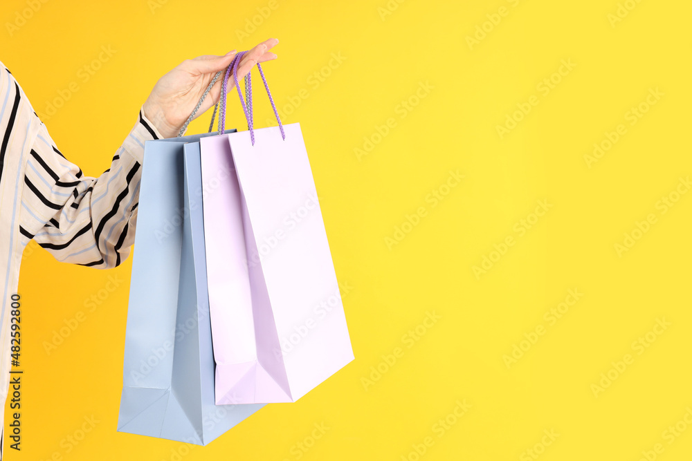Woman holds shop bags on a yellow background