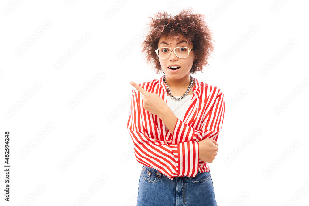 Shocked kazakh girl face with afro curls looks surprised on white studio background points finger at copy space Shocked kazakh girl face with afro curls looks surprised on white studio background points finger at copy space