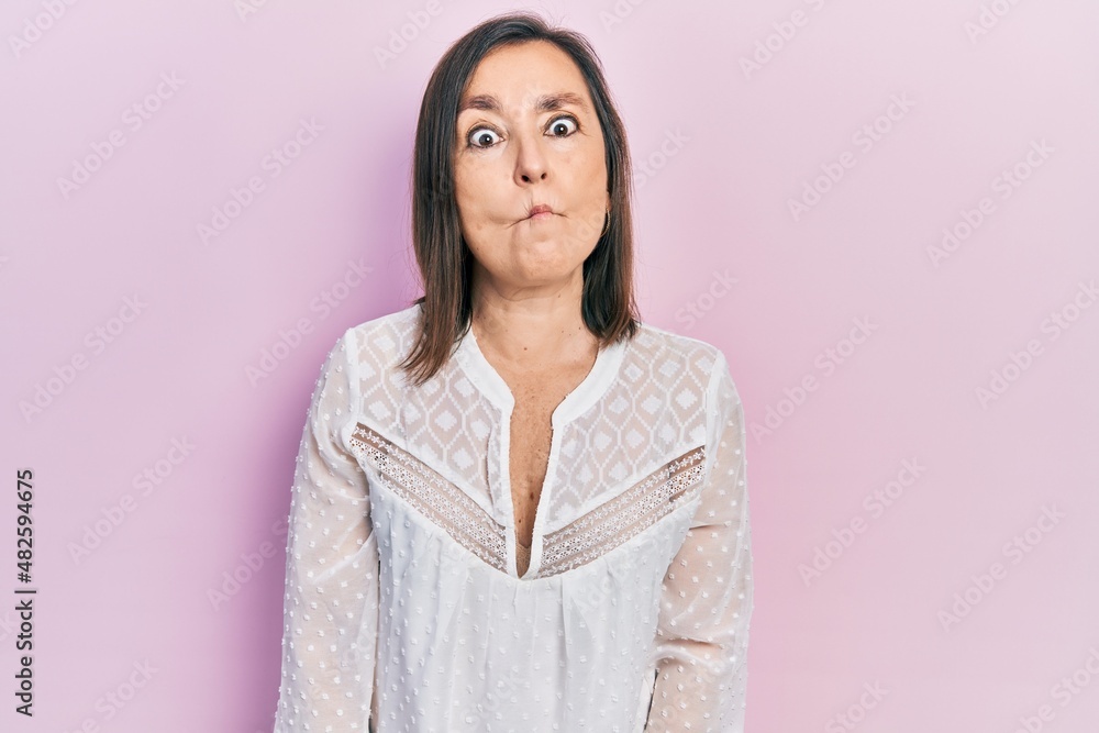 Middle age hispanic woman wearing casual clothes making fish face with lips, crazy and comical gesture. funny expression. Middle age hispanic woman wearing casual clothes making fish face with lips, crazy and comical gesture. funny expression.