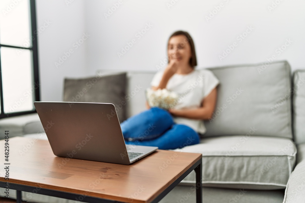 Middle age hispanic woman watching a movie eating popcorn at home Middle age hispanic woman watching a movie eating popcorn at home