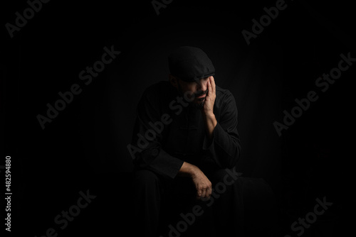 man dressed in black, depressed and lonely..Boy with beard, mustache and black beret on black background. Concept wait, pandemic, negativity, depression, drama, bad moments.