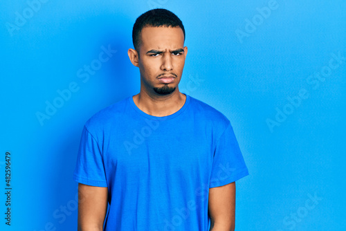 Young african american man wearing casual blue t shirt skeptic and nervous, frowning upset because of problem. negative person.