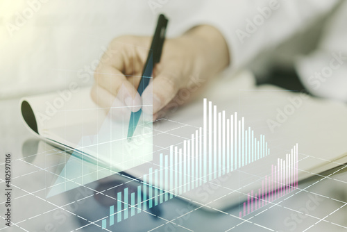 Double exposure of abstract creative financial diagram with hand writing in notebook on background, banking and accounting concept