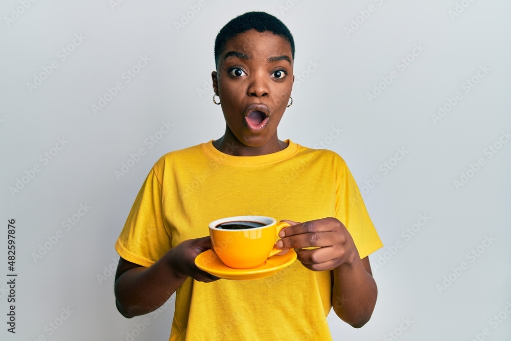 Young african american woman holding coffee afraid and shocked with surprise and amazed expression, fear and excited face. Young african american woman holding coffee afraid and shocked with surprise and amazed expression, fear and excited face.