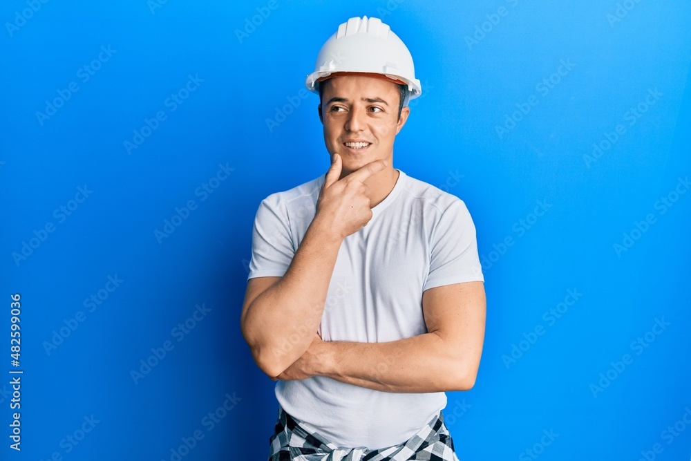 Handsome young man wearing builder uniform and hardhat with hand on chin thinking about question, pensive expression. smiling with thoughtful face. doubt concept. Handsome young man wearing builder uniform and hardhat with hand on chin thinking about question, pensive expression. smiling with thoughtful face. doubt concept.