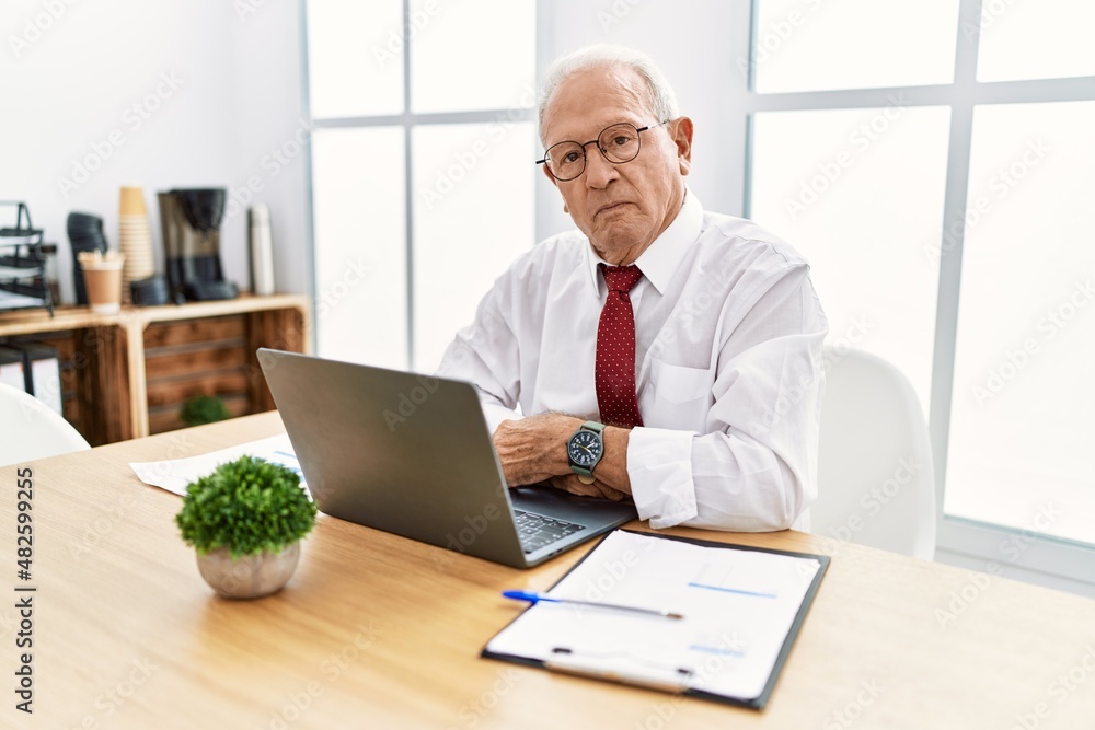 Senior man working at the office using computer laptop relaxed with serious expression on face. simple and natural looking at the camera. Senior man working at the office using computer laptop relaxed with serious expression on face. simple and natural looking at the camera.