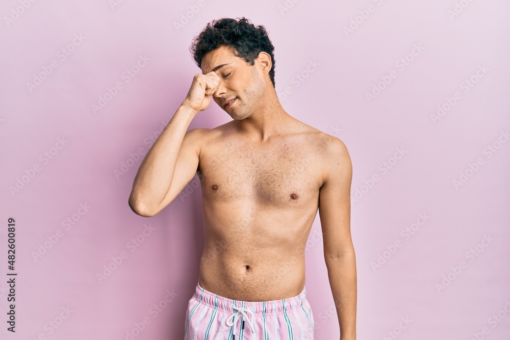 Fototapeta premium Young handsome man wearing swimwear shirtless tired rubbing nose and eyes feeling fatigue and headache. stress and frustration concept.