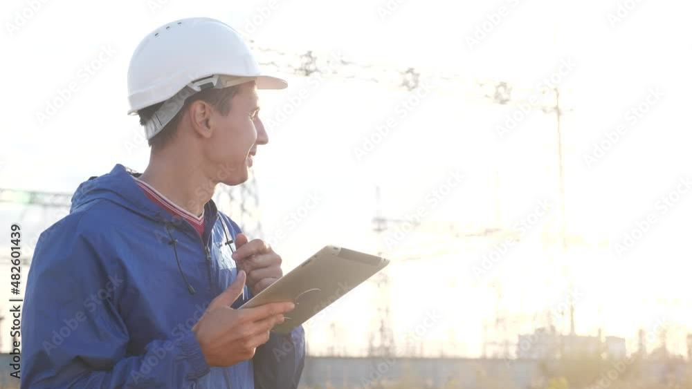 electrical worker engineer a working with digital tablet, near tower with power electricity. business energy technology industry concept. electrical studying reading documents on tablet electrical worker engineer a working with digital tablet, near tower with power electricity. business energy technology industry concept. electrical studying reading documents on tablet