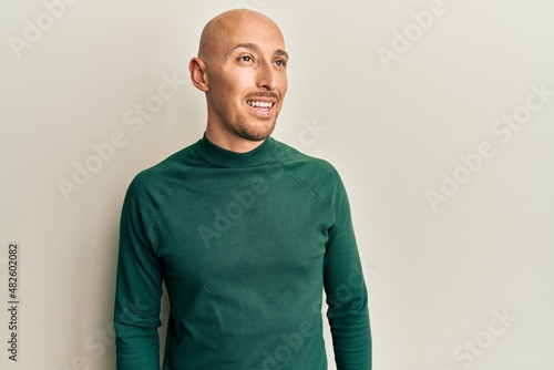 Bald man with beard wearing casual turtleneck sweater looking to side, relax profile pose with natural face and confident smile. © Krakenimages.com