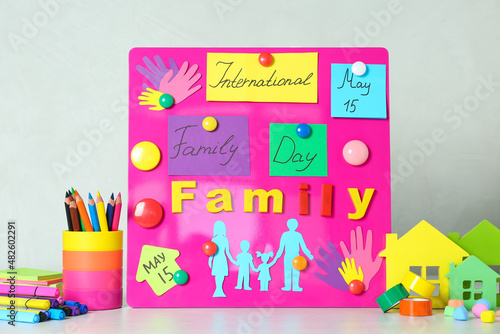 Fototapeta Naklejka Na Ścianę i Meble -  Magnetic board with text International Family Day and paper cutouts on white table