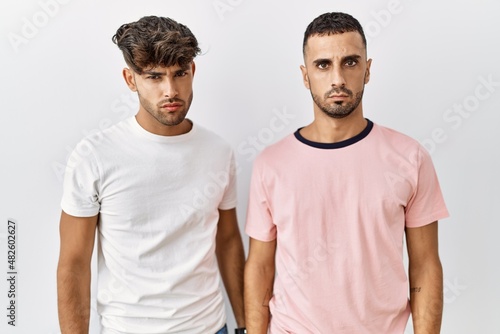 Young gay couple standing over isolated background skeptic and nervous, frowning upset because of problem. negative person.