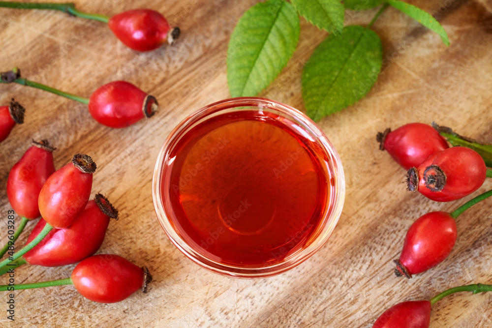A bottle of rose hip seed oil with fresh rosehips, top view A bottle of rose hip seed oil with fresh rosehips, top view