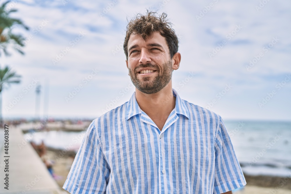 Young hispanic man smiling happy standing at the beach. Young hispanic man smiling happy standing at the beach.