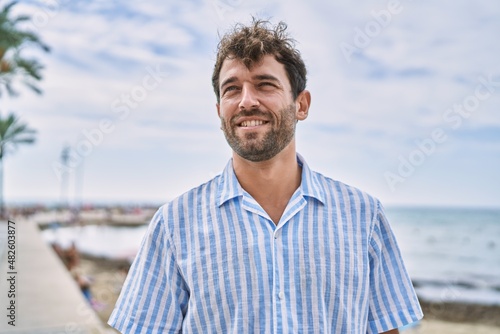 Young hispanic man smiling happy standing at the beach. © Krakenimages.com