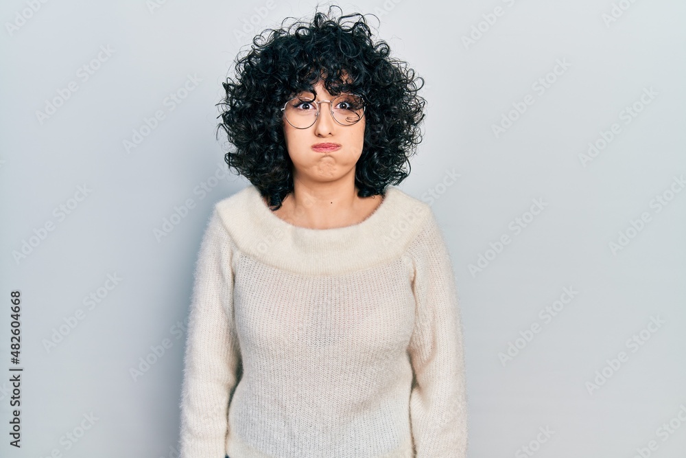 Young middle east woman wearing casual white tshirt puffing cheeks with funny face. mouth inflated with air, crazy expression. Young middle east woman wearing casual white tshirt puffing cheeks with funny face. mouth inflated with air, crazy expression.