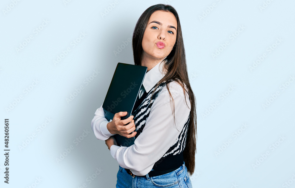 Young brunette teenager hugging laptop with love looking at the camera blowing a kiss being lovely and sexy. love expression. Young brunette teenager hugging laptop with love looking at the camera blowing a kiss being lovely and sexy. love expression.