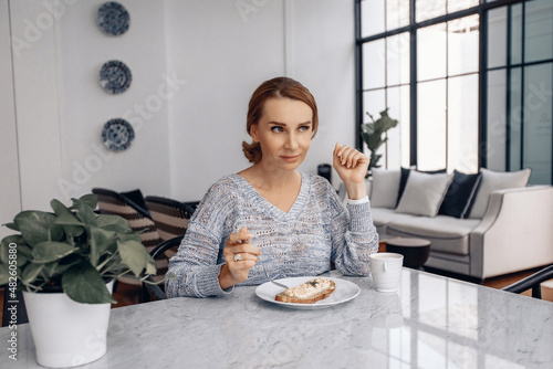 Everyday concept. Daily life. Attractive adorable afult woman wearing sweater is about to dine in her white apartment photo