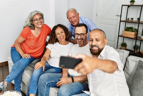 Group of middle age friends smiling happy make selfie by the smartphone at home.