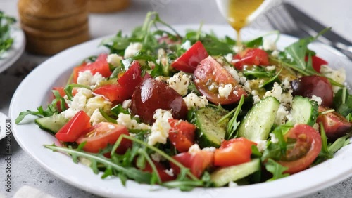 Dressing salad with olive oil lemon mustard vinaigrette. Healthy spring or summer vegetable salad with goat cheese