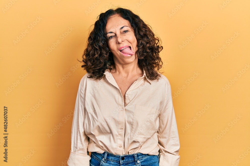 Middle age hispanic woman wearing casual clothes sticking tongue out happy with funny expression. emotion concept. Middle age hispanic woman wearing casual clothes sticking tongue out happy with funny expression. emotion concept.