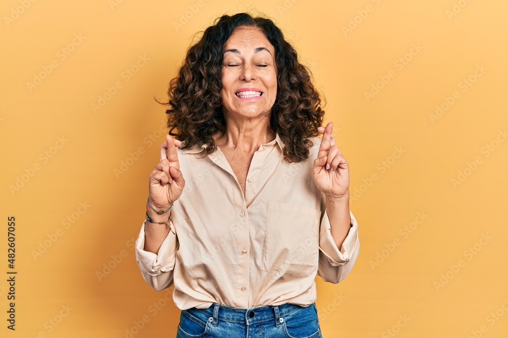 Middle age hispanic woman wearing casual clothes gesturing finger crossed smiling with hope and eyes closed. luck and superstitious concept. Middle age hispanic woman wearing casual clothes gesturing finger crossed smiling with hope and eyes closed. luck and superstitious concept.