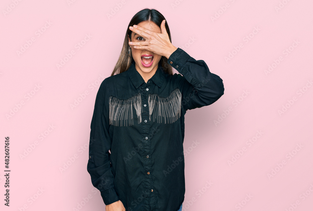 Young hispanic woman wearing casual clothes peeking in shock covering face and eyes with hand, looking through fingers with embarrassed expression. Young hispanic woman wearing casual clothes peeking in shock covering face and eyes with hand, looking through fingers with embarrassed expression.