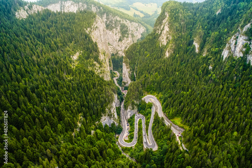 Amazing mountain winding road in Romania. Aerial view of Bicaz Gorges in the summer landscape with a curved motorway between the tall mountains and the green forest.