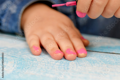 Wallpaper Mural A small child looks with attention at his painted nails with nail polish. Torontodigital.ca
