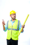 Young indian engineer wearing hardhat and using smartphone on white background.