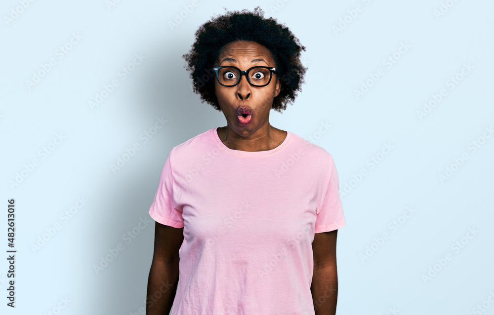 African american woman with afro hair wearing casual clothes and glasses afraid and shocked with surprise expression, fear and excited face. African american woman with afro hair wearing casual clothes and glasses afraid and shocked with surprise expression, fear and excited face.