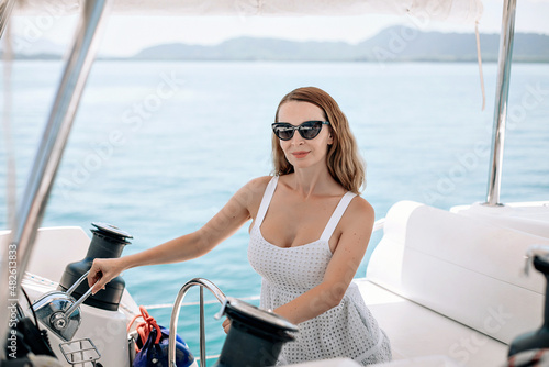 Portrait of an adult pretty cute lovely girl wearing squirrel dress and sunglasses and sitting at the wheel of her yacht, concentrating on the road. Vacation concept