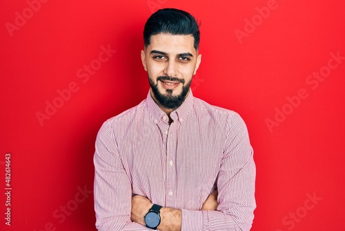 Handsome man with beard wearing casual red shirt happy face smiling with crossed arms looking at the camera. positive person.