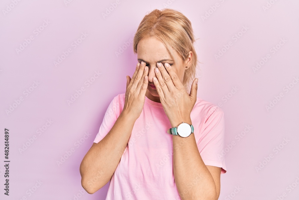 Young blonde woman wearing casual pink t shirt rubbing eyes for fatigue and headache, sleepy and tired expression. vision problem Young blonde woman wearing casual pink t shirt rubbing eyes for fatigue and headache, sleepy and tired expression. vision problem