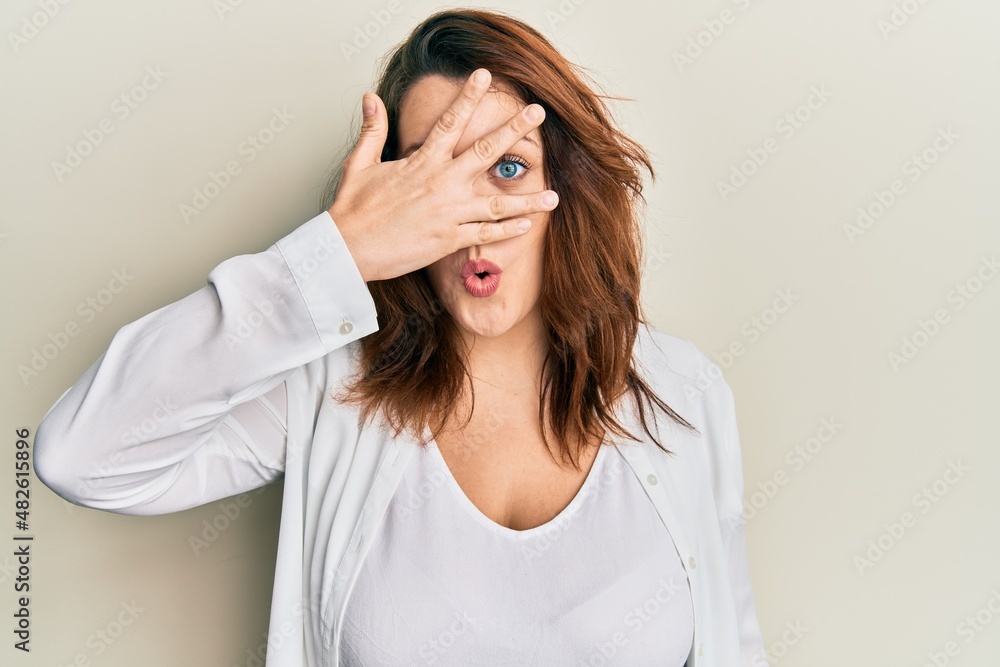 Young caucasian woman wearing casual clothes peeking in shock covering face and eyes with hand, looking through fingers afraid Young caucasian woman wearing casual clothes peeking in shock covering face and eyes with hand, looking through fingers afraid
