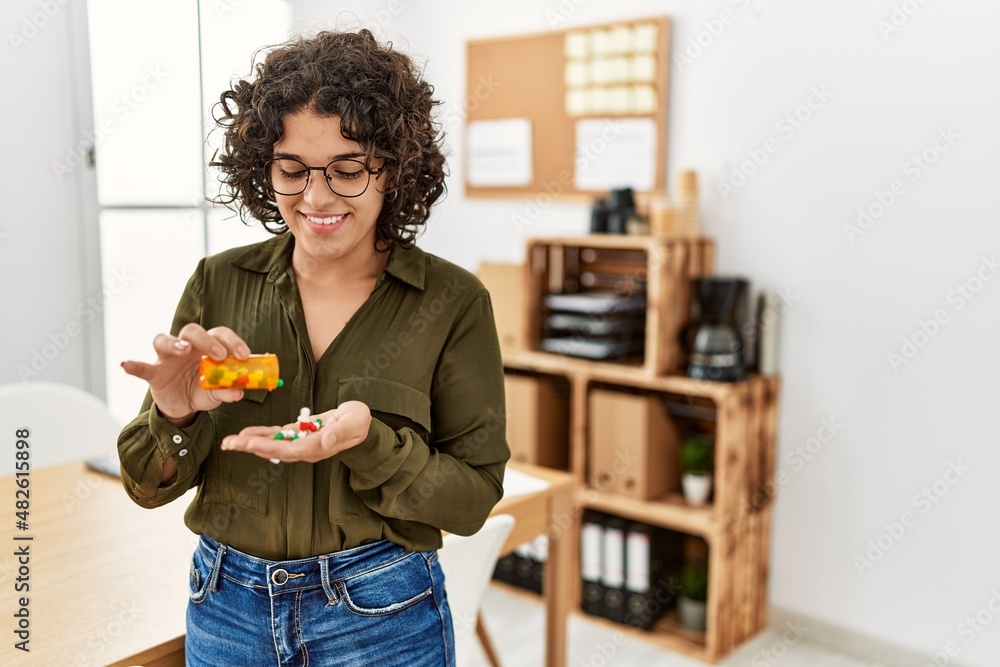 Young hispanic woman smiling confident taking pills at office Young hispanic woman smiling confident taking pills at office