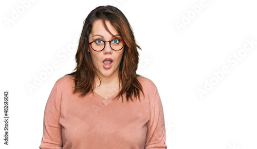 Young plus size woman wearing casual clothes and glasses afraid and shocked with surprise and amazed expression, fear and excited face.