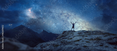 Hiker under a starry night sky in the mountains