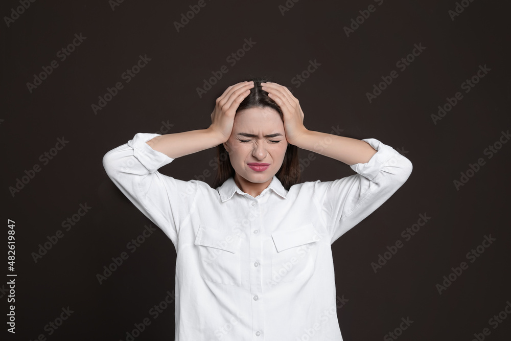 Young woman suffering from headache on brown background Young woman suffering from headache on brown background