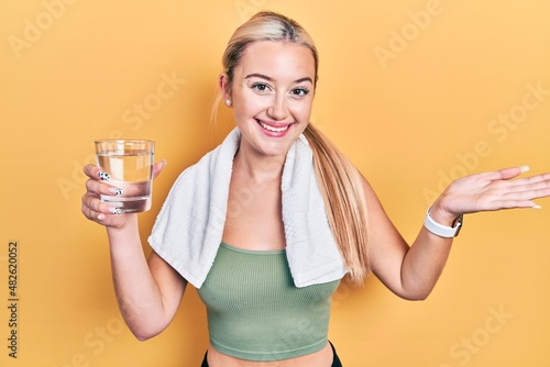 Young blonde girl wearing sportswear drinking glass of water celebrating achievement with happy smile and winner expression with raised hand © Krakenimages.com