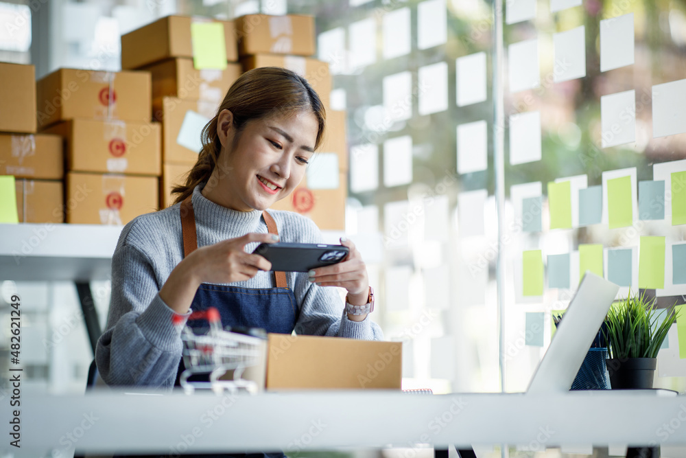 Startup SME small business entrepreneur SME or freelance Asian woman using a laptop with box, Young success Asian woman with her hand lift up, online marketing packaging box and delivery, SME concept. Startup SME small business entrepreneur SME or freelance Asian woman using a laptop with box, Young success Asian woman with her hand lift up, online marketing packaging box and delivery, SME concept.