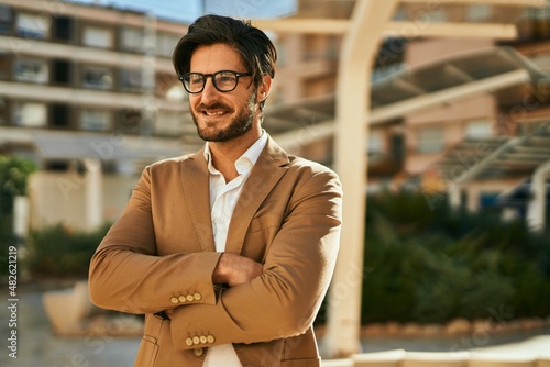 Young hispanic businessman smiling happy standing at the city.