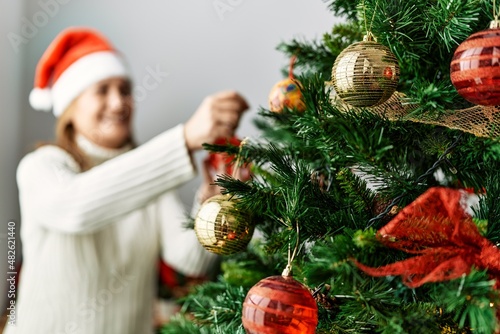 Middle age caucasian woman smiling confident decorating christmas tree at home