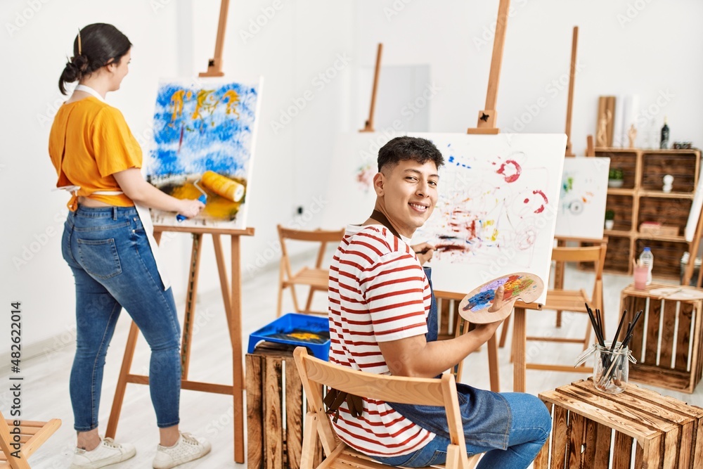 Obraz premium Two hispanic paint students smiling happy painting at art studio.