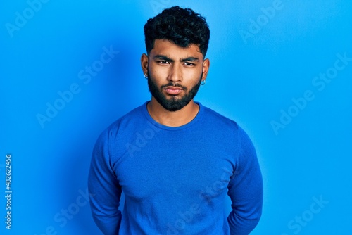 Arab man with beard wearing casual blue sweater skeptic and nervous, frowning upset because of problem. negative person.