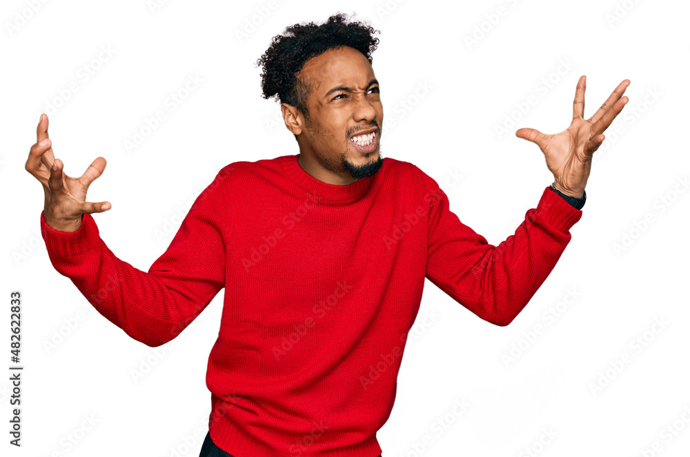 Young african american man with beard wearing casual winter sweater crazy and mad shouting and yelling with aggressive expression and arms raised. frustration concept. Young african american man with beard wearing casual winter sweater crazy and mad shouting and yelling with aggressive expression and arms raised. frustration concept.