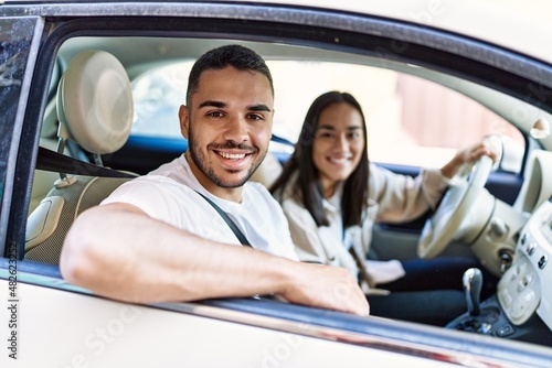 Young hispanic couple smiling happy driving car at the city.