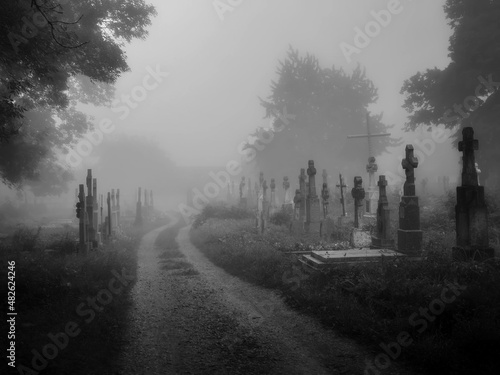 Dark ancient cemetery in the fog. Crosses and graves in the old abandoned cemetery. Place of burial. Black and White photo photo